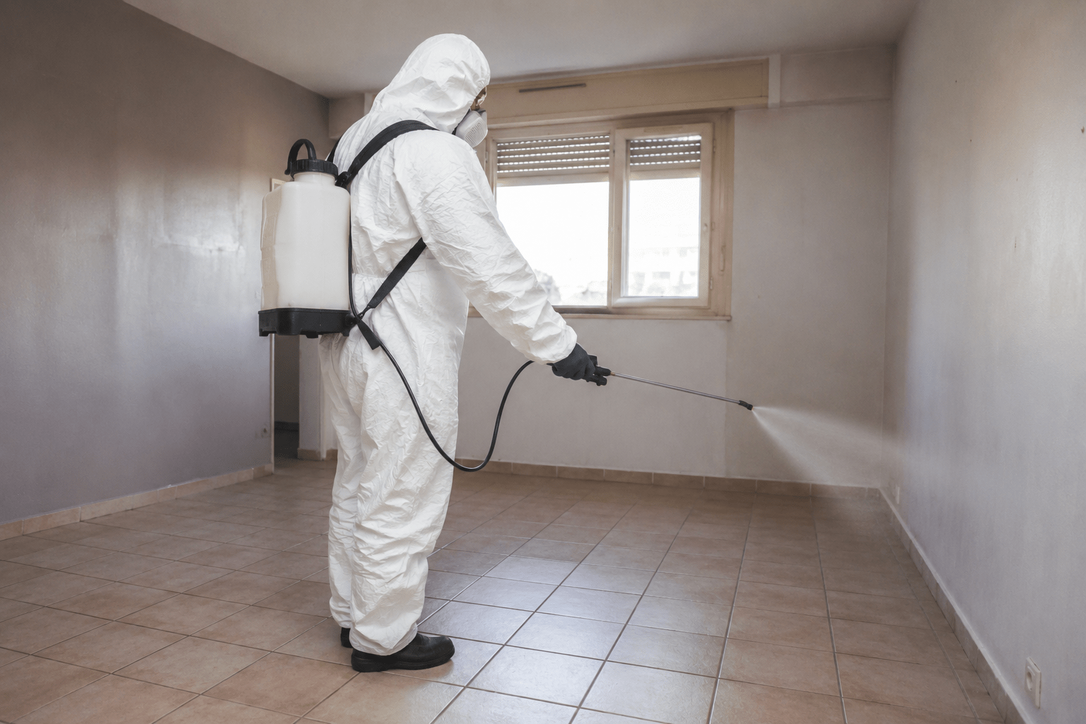 Technicien en combinaison réalisant une désinfection après débarras